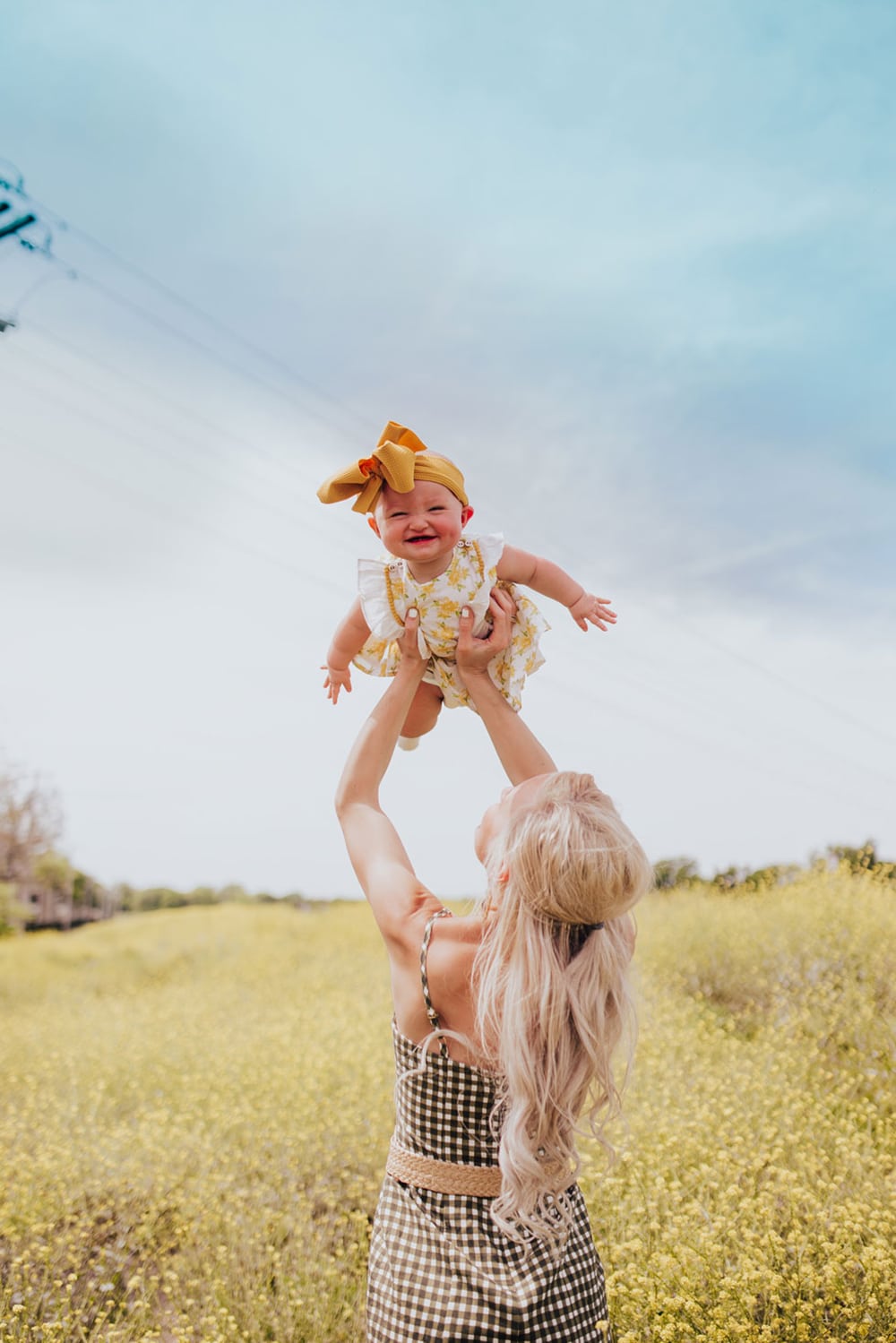 family photo ideas - mommy and me photography tips and poses - holding baby in air - yellow flower field